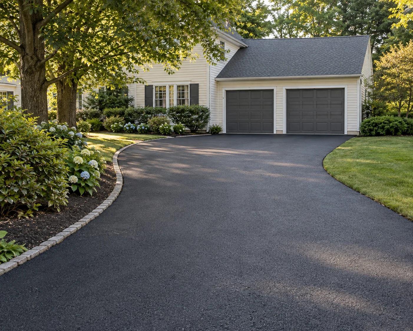 After paving: fresh charcoal asphalt and neatly finished driveway edges at a cream-sided home