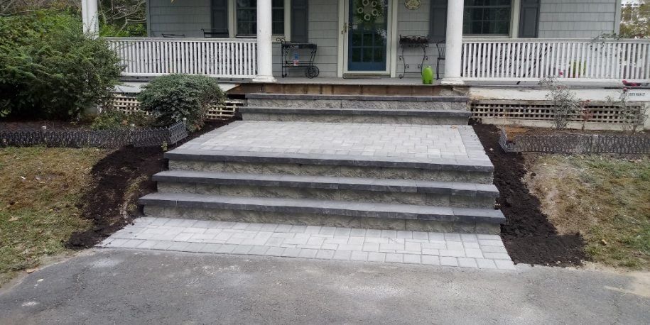 Wide paver entrance and stone steps leading to a front porch