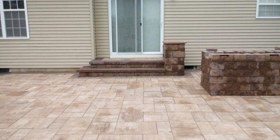 Paver patio and steps connected by a stone wall