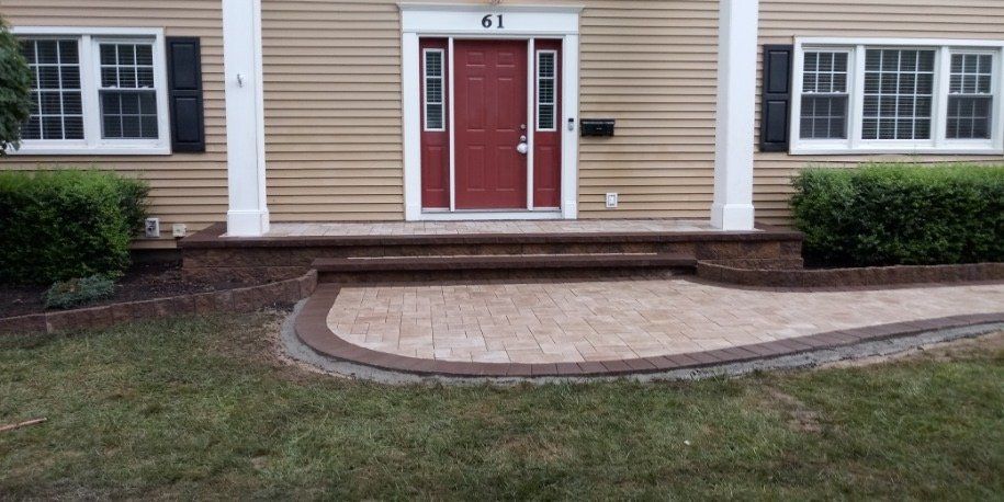 Paver entrance leading to a red front door
