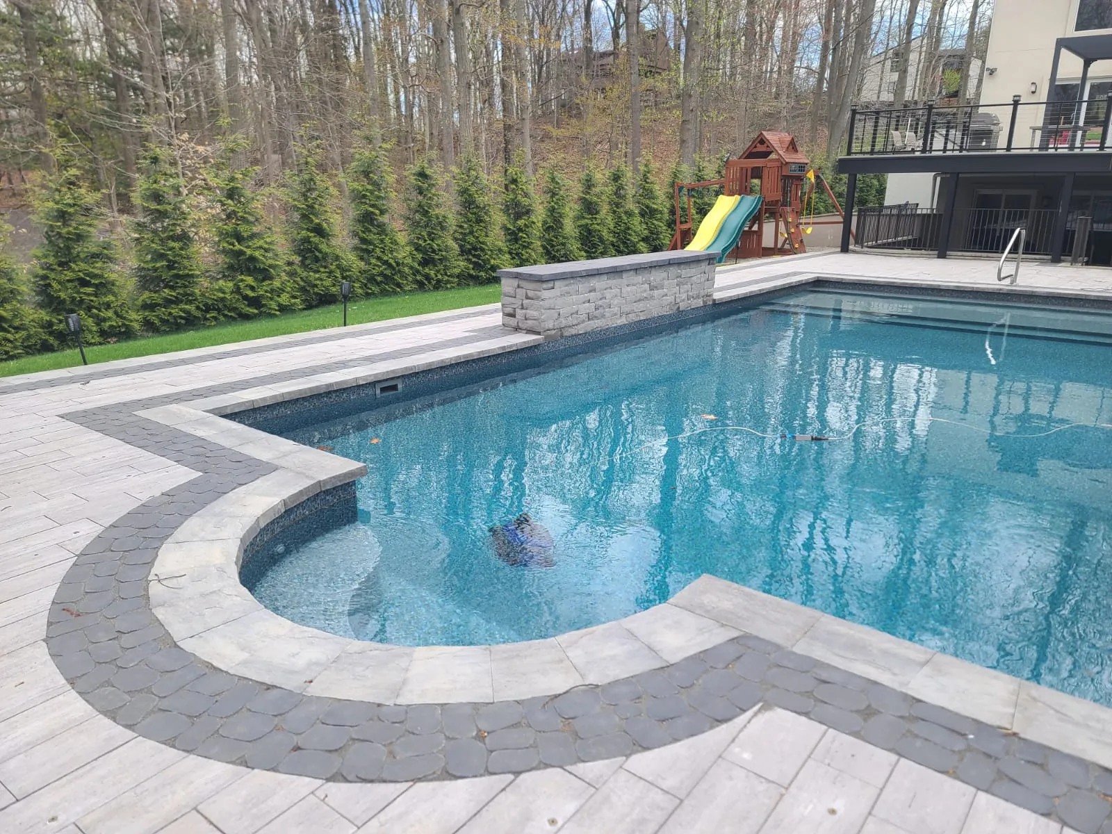 Curved pool coping with a contrasting paver border and nearby sitting wall