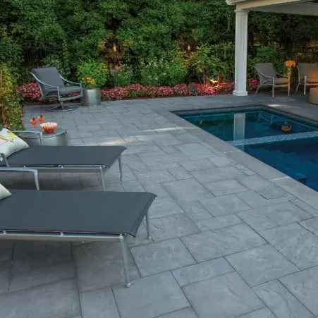 Gray paver pool patio with matching coping beside a covered seating area