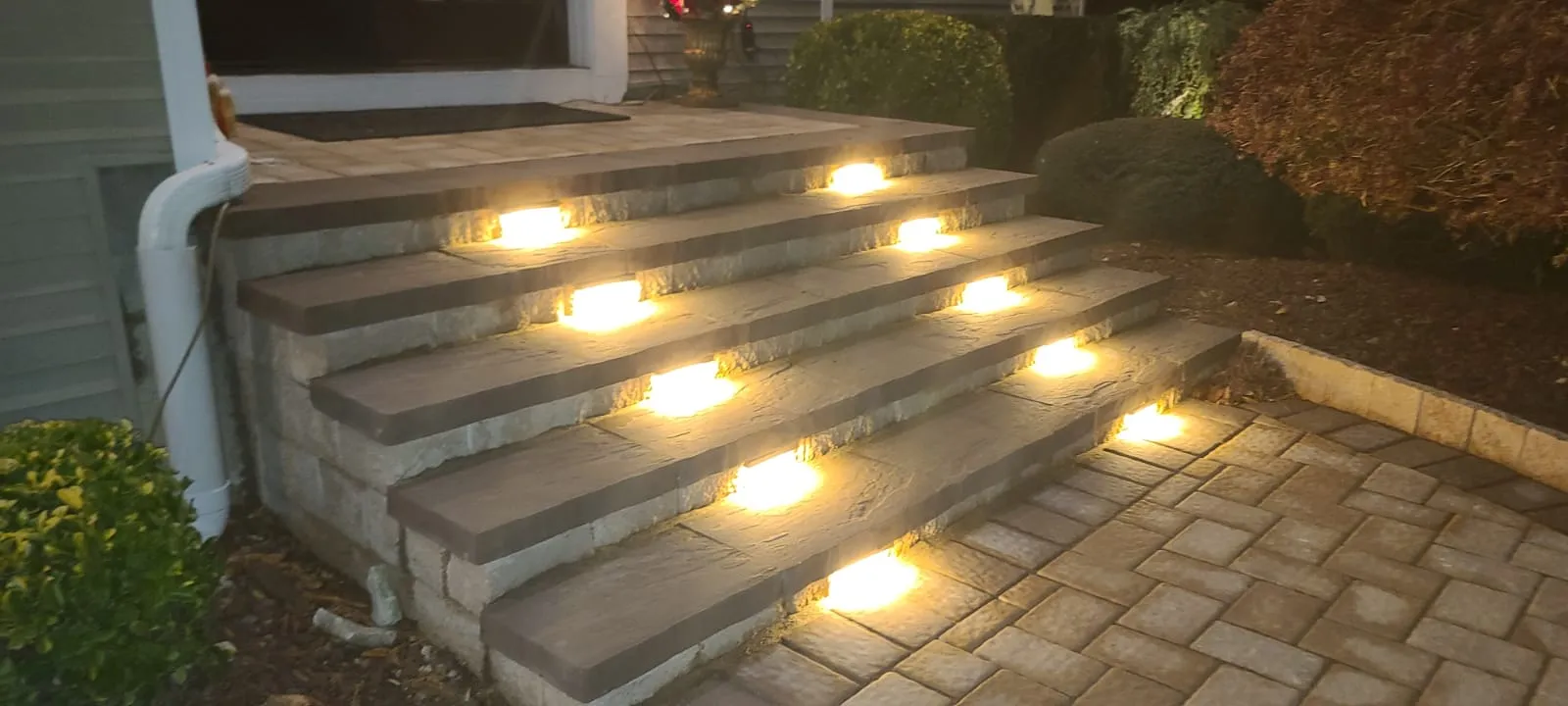 Wide paver entrance steps with dark caps and integrated lights, built by New Jersey Pavers