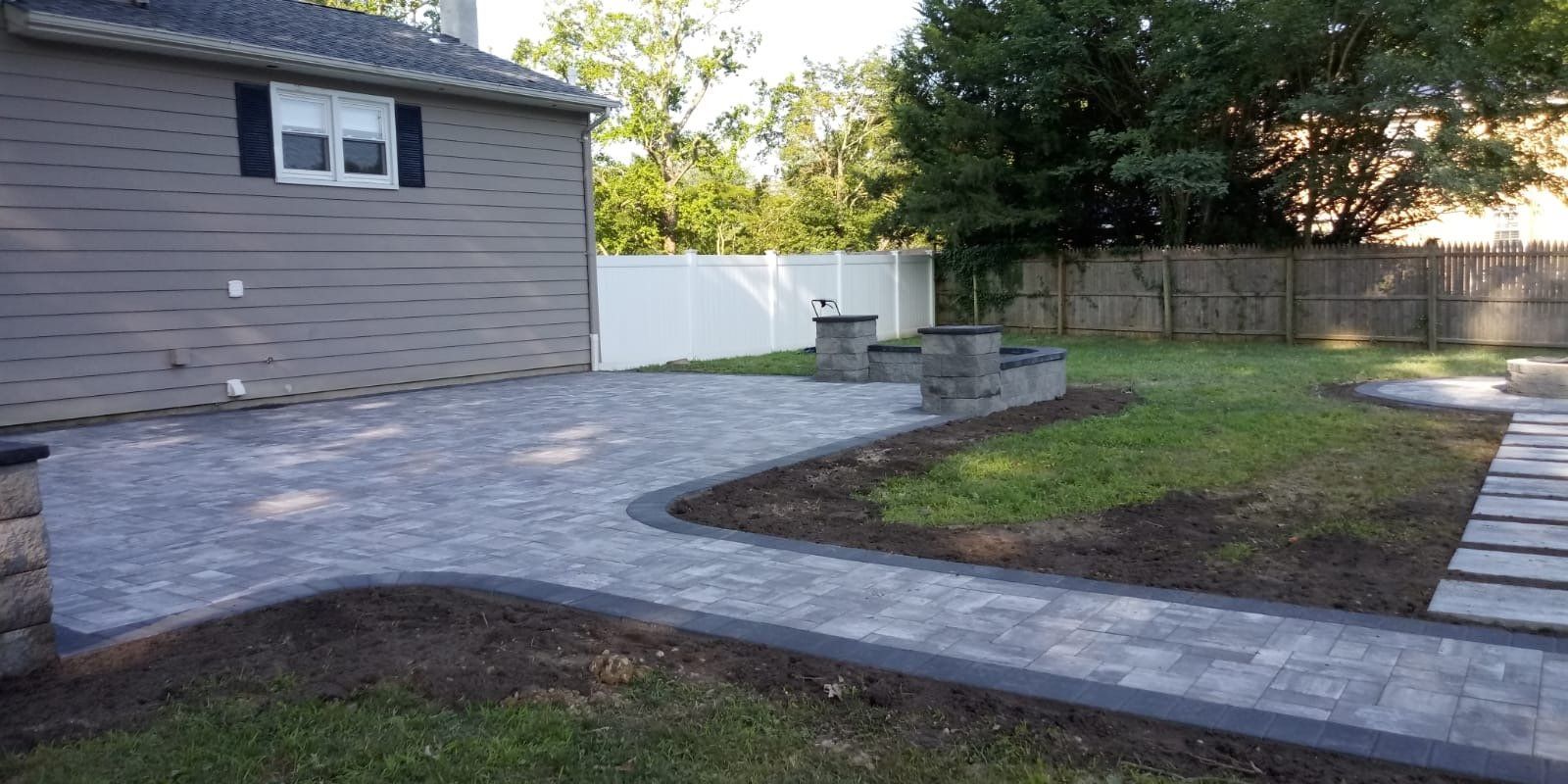 Large gray paver patio in a landscaped backyard