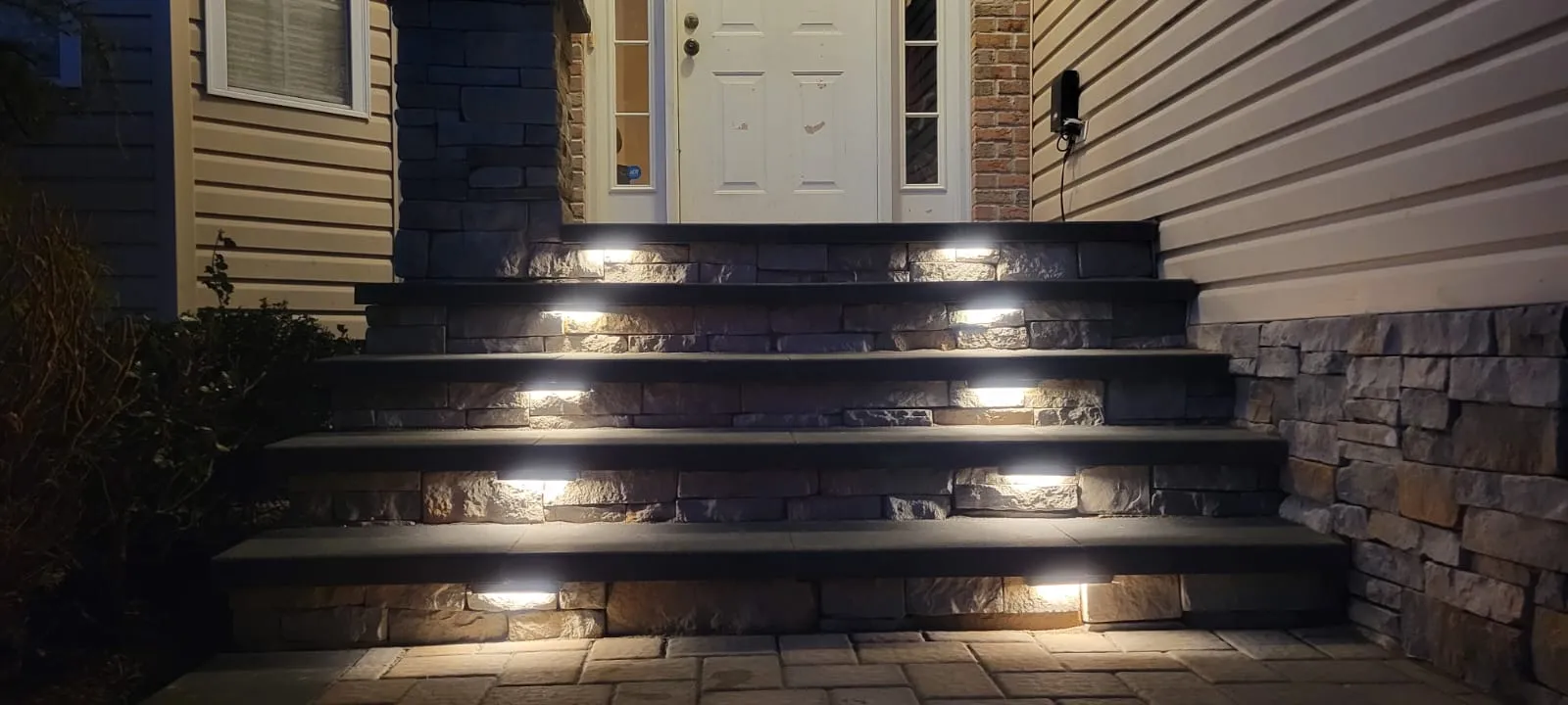 Stone front steps with dark caps and built-in evening lights, built by New Jersey Pavers
