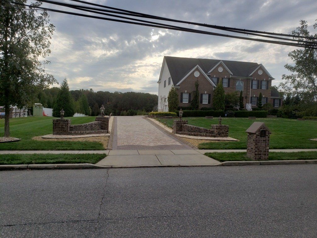 Paver driveway approaching a brick home