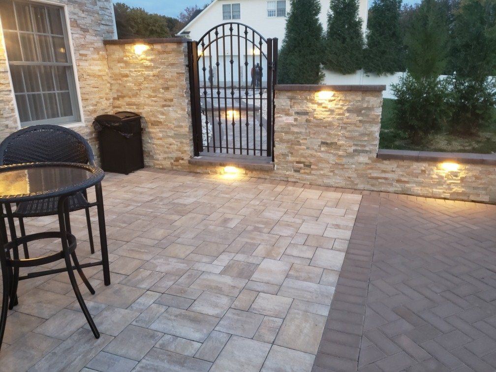 Stone wall caps, a garden gate, and built-in lighting around a paver patio