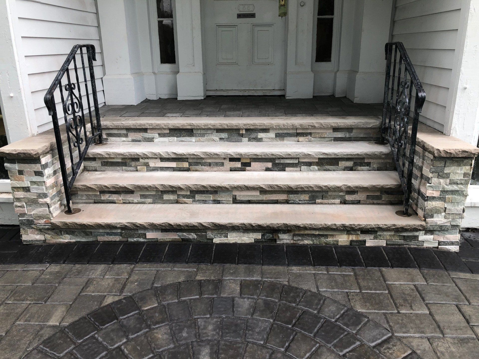 Stone-faced front steps with a paver landing