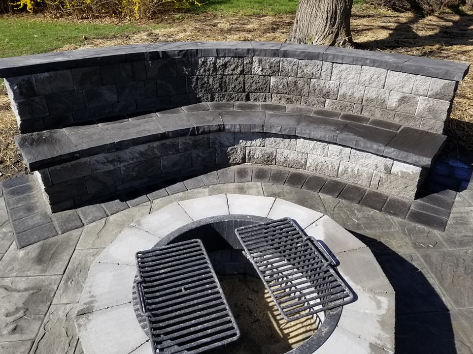 Round outdoor firepit surrounded by a paver seating area