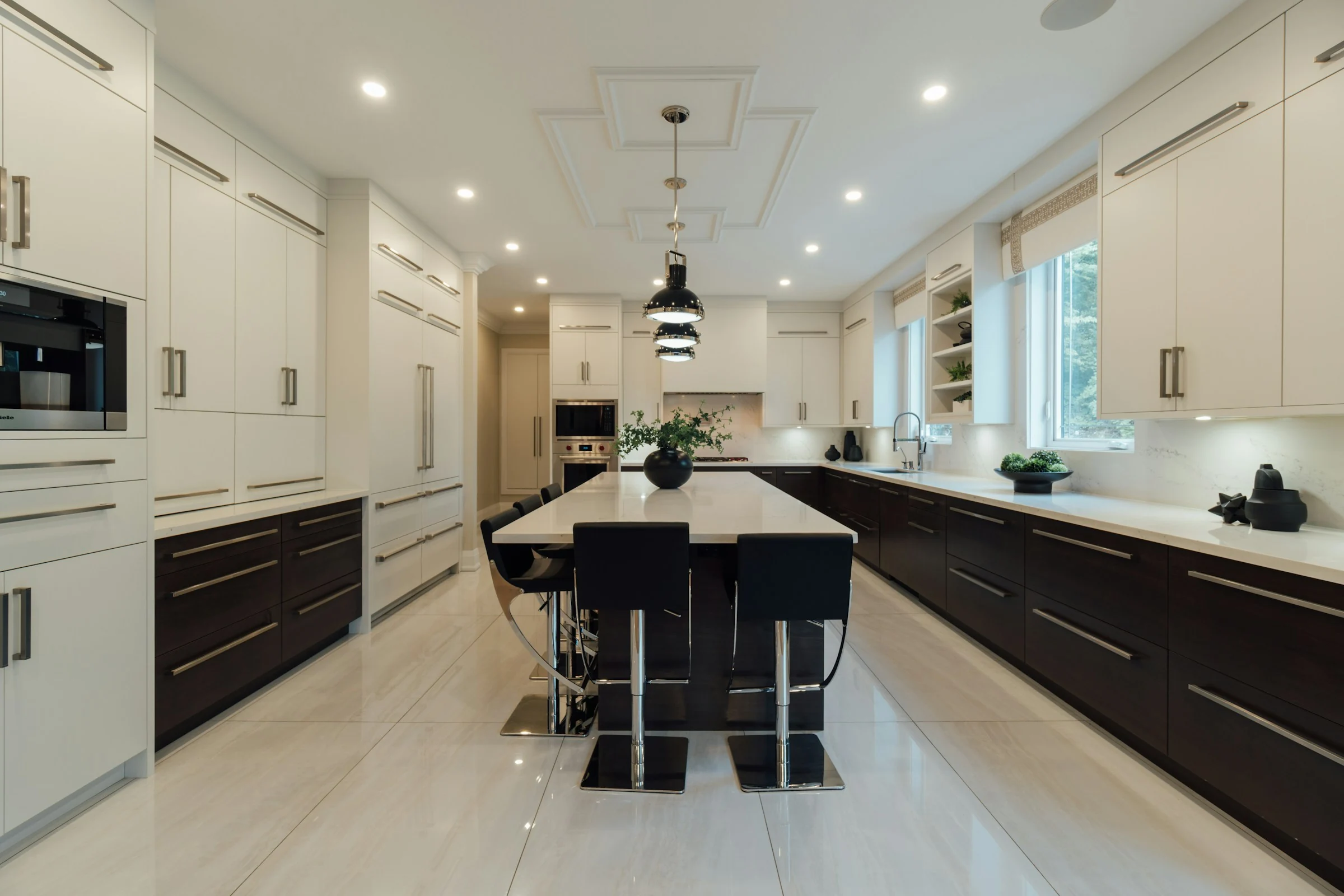 Kitchen with white and dark wood cabinetry, stone countertops, island seating and updated lighting